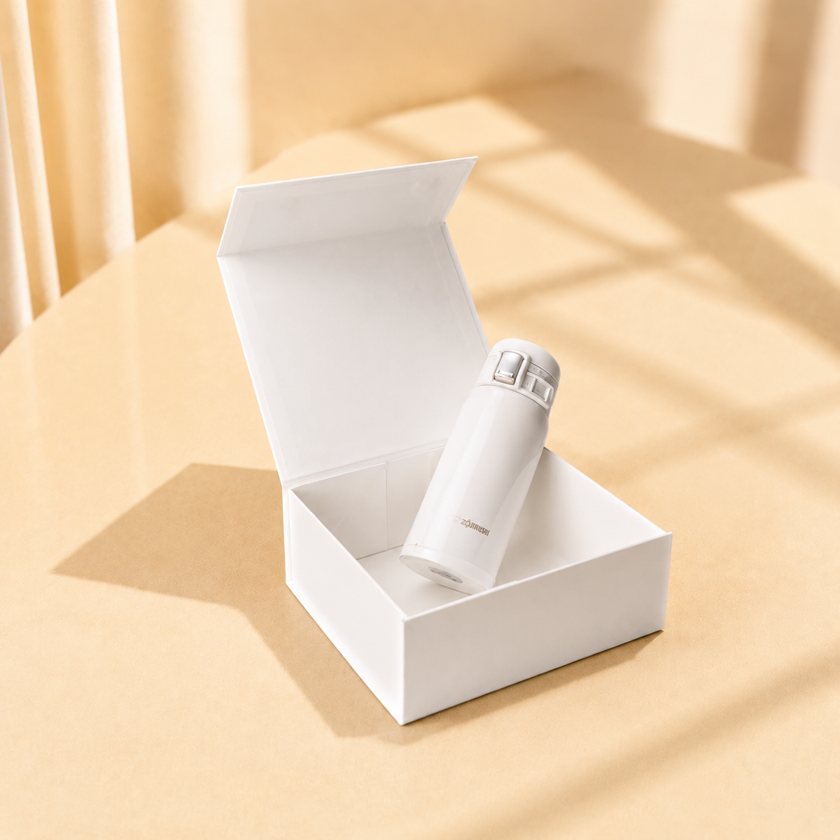 Open white jewelry gift box holding a small bottle